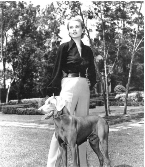 A vintage photograph of a Weimaraner and Grace Kelly outdoors.